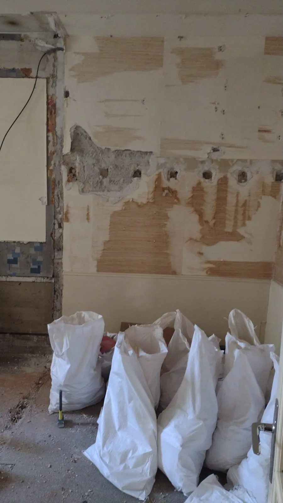 Sacs blancs regroupés dans une pièce dont les revêtements muraux ont été retirés.